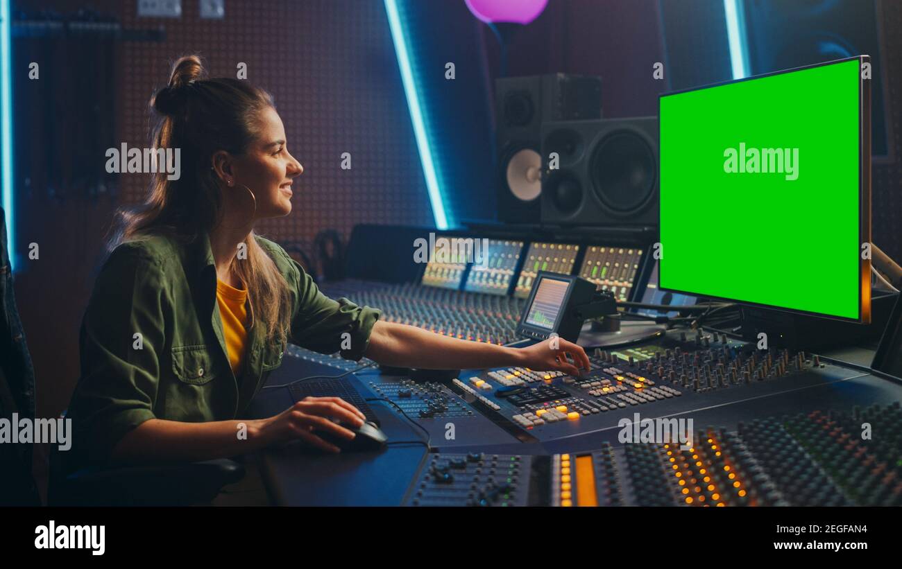 Ritratto di elegante femmina Audio Engineer Produttore che lavora in Music Record Studio, utilizza schermo verde computer Display, Mixer Board, Control Desk a. Foto Stock
