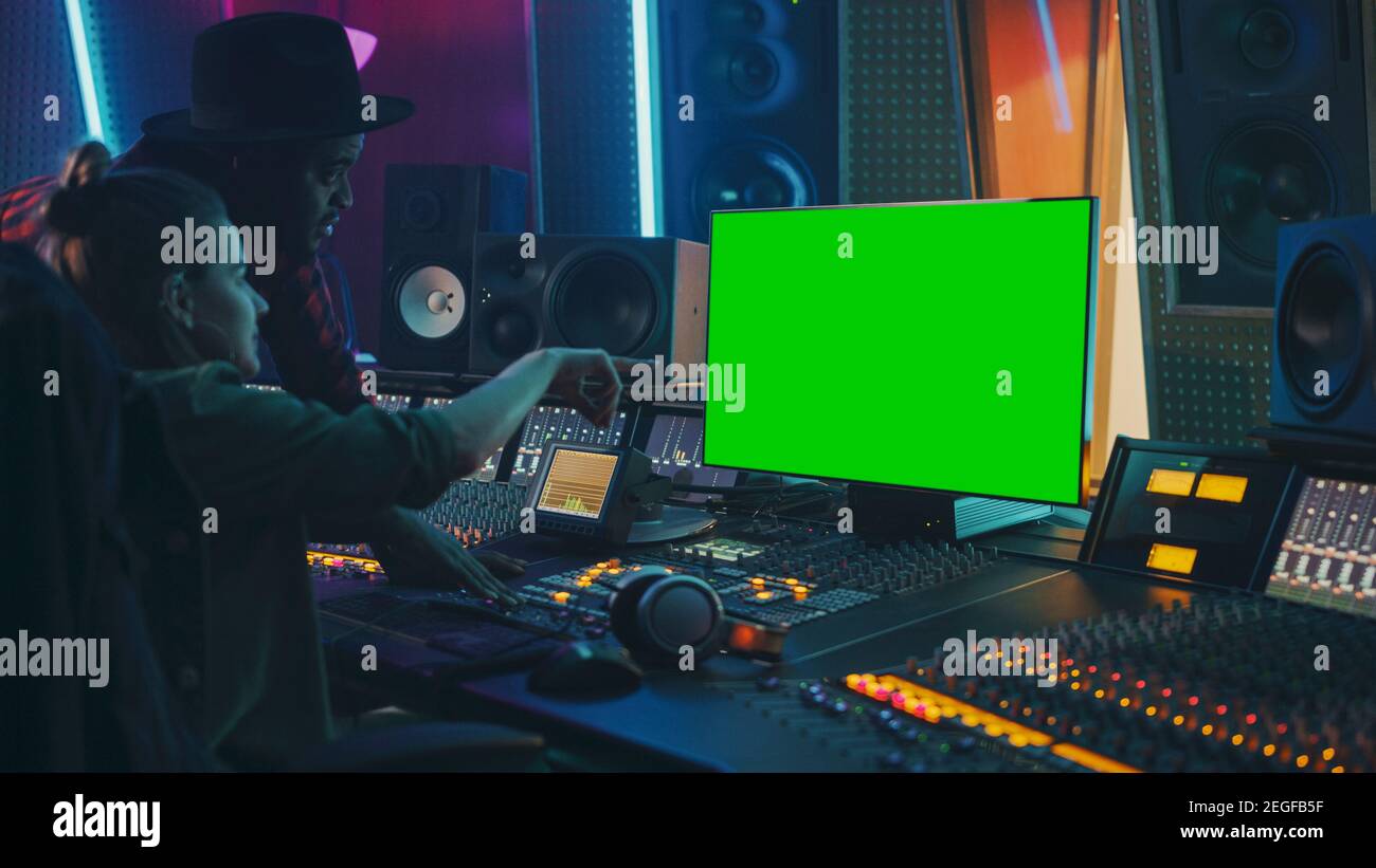 Produttore e ingegnere audio lavorando insieme in Music Record Studio su un nuovo album, utilizzare il computer con schermo verde, Control Desk per mixare e creare Foto Stock