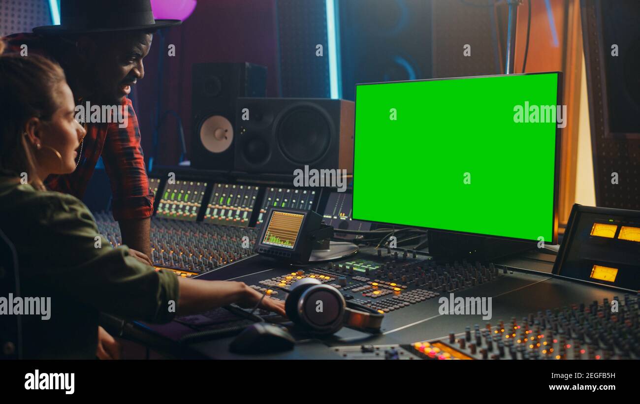 Produttore e ingegnere audio lavorando insieme in Music Record Studio su un nuovo album, utilizzare il computer con schermo verde, Control Desk per mixare e creare Foto Stock