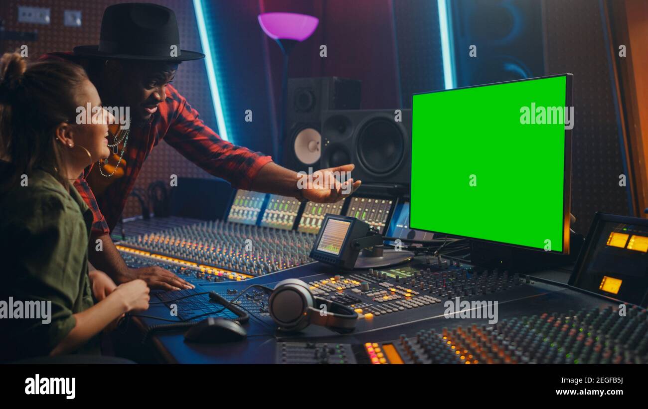 Produttore e ingegnere audio lavorando insieme in Music Record Studio su un nuovo album, utilizzare il computer con schermo verde, Control Desk per mixare e creare Foto Stock