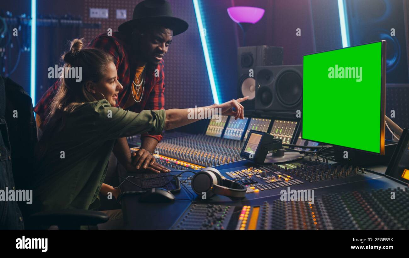 Produttore e ingegnere audio lavorando insieme in Music Record Studio su un nuovo album, utilizzare il computer con schermo verde, Control Desk per mixare e creare Foto Stock