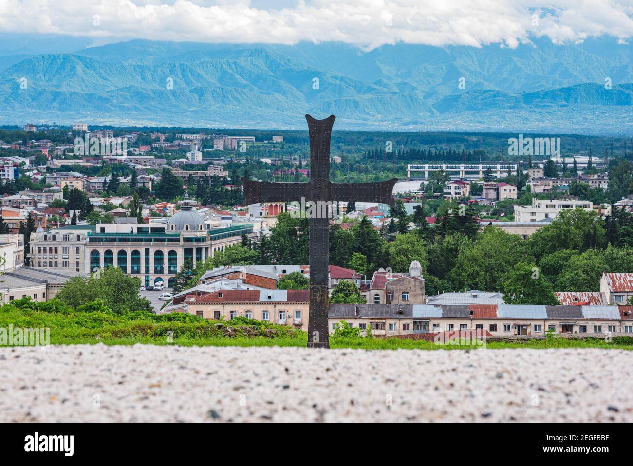 Croce di metallo nero con panorama della città di Kutaisi sullo sfondo, un monumento vicino alla Cattedrale di Bagrati, Kutaisi, Georgia Foto Stock