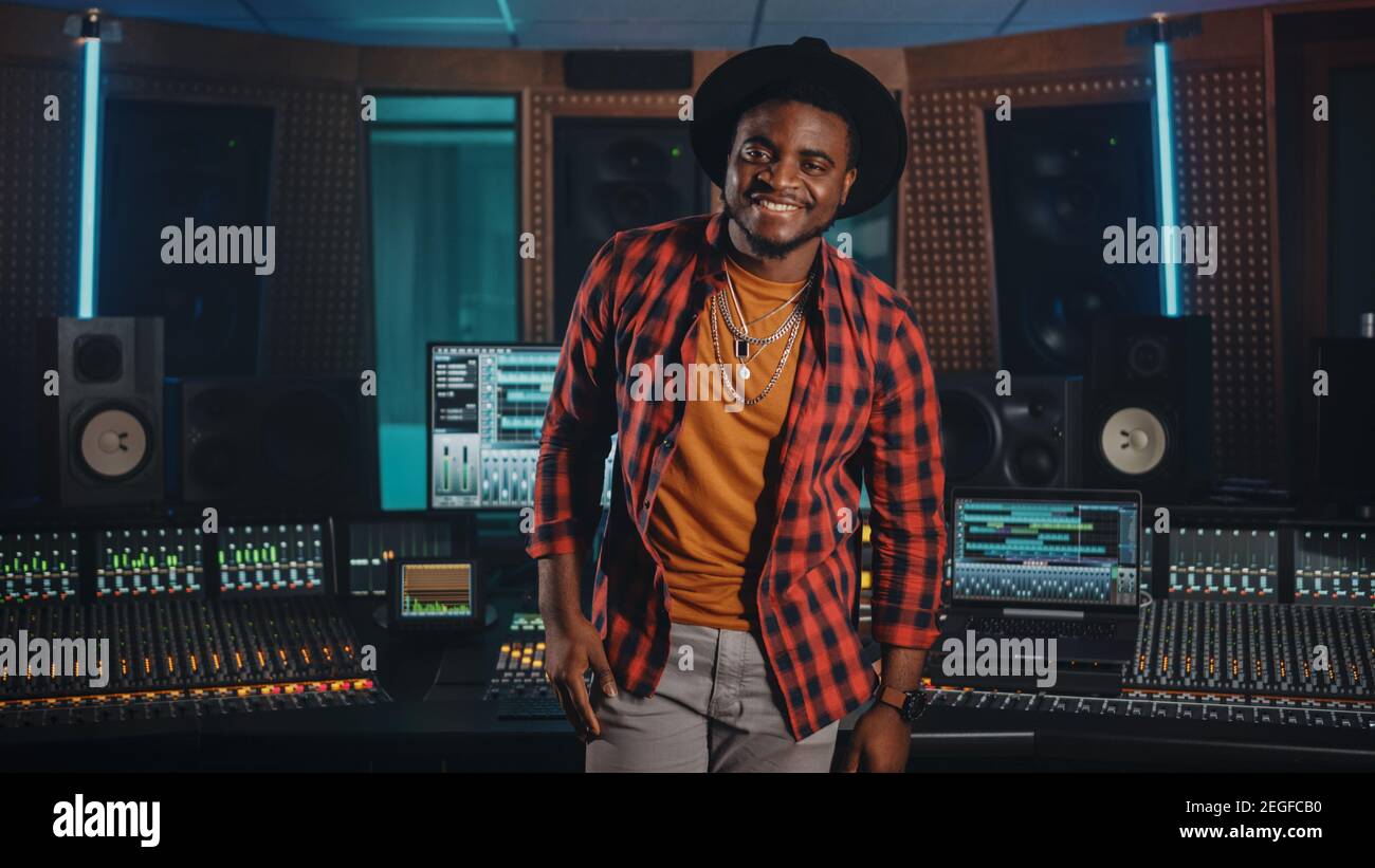 Ritratto di Young Black Artist, Musician, Audio Engineer, Produttore che indossa un cappello alla moda e che si trova in piedi in Music Record Studio. Nel controllo background Foto Stock