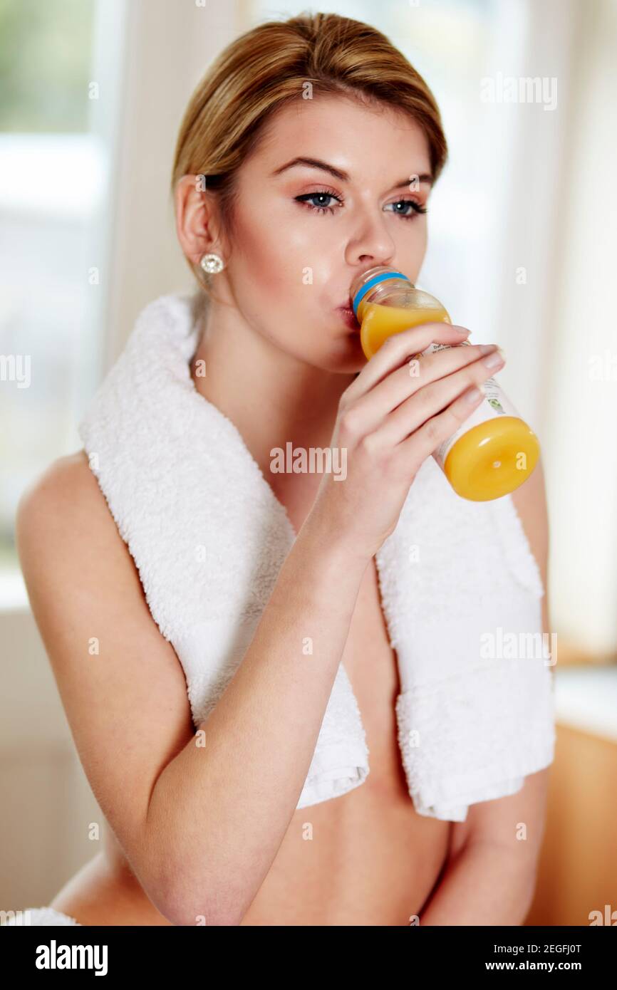 Donna che beve una bottiglia di succo d'arancia fresco Foto Stock