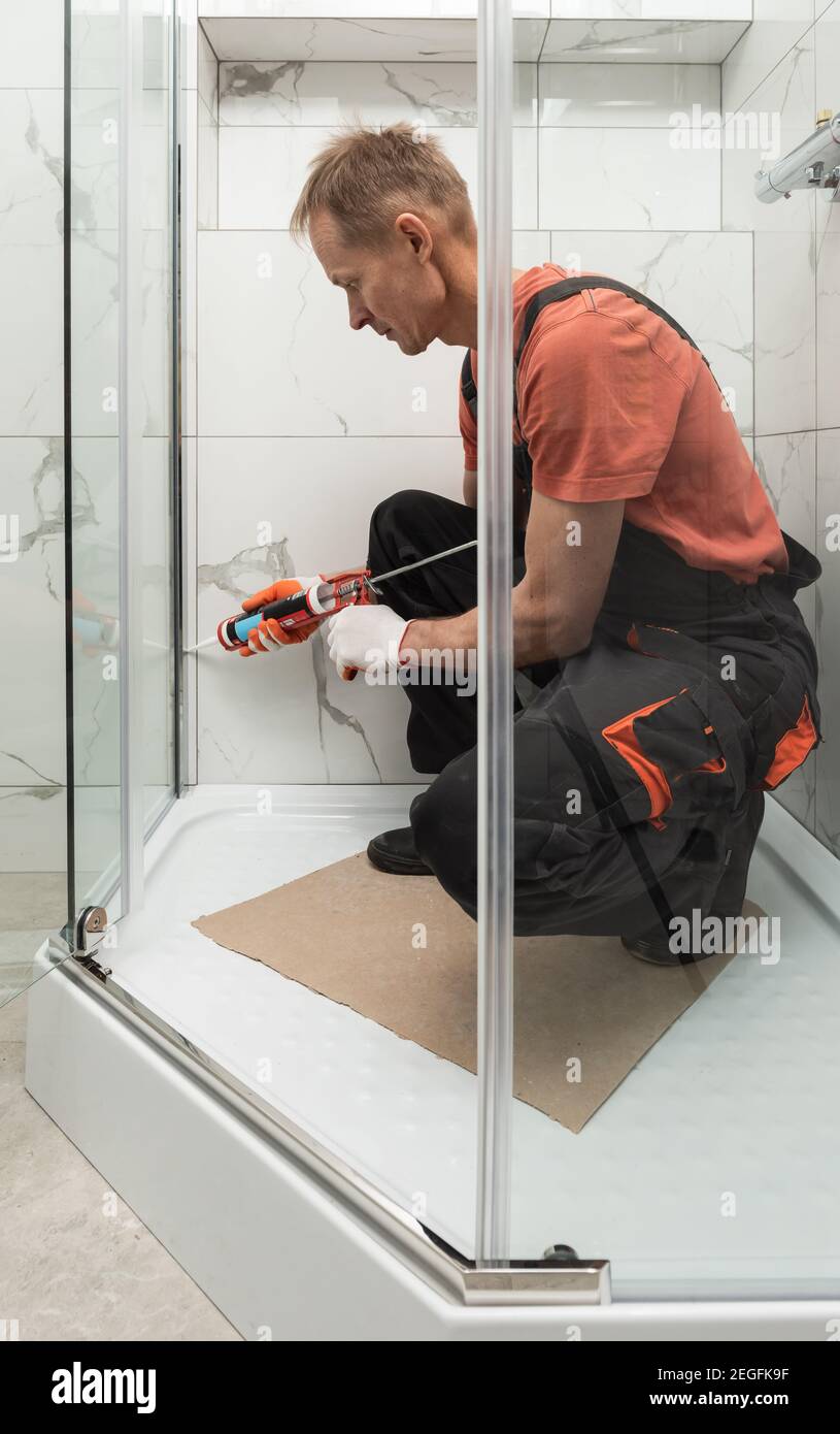 Il lavoratore sta sigillando il box doccia con silicone per evitare perdite  Foto stock - Alamy
