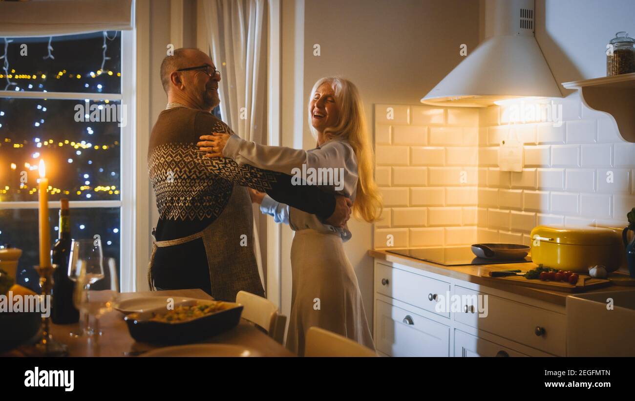 Happy Senior Couple in Love hanno serata romantica, Danza in cucina, festeggiando l'anniversario. Serata romantica con vino, tavolo festivo in Foto Stock