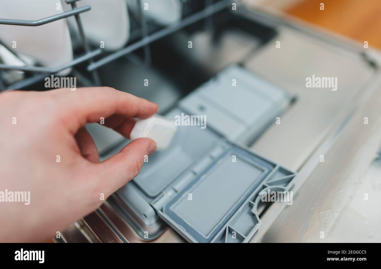 Uomo che mette la pastiglia detergente in lavastoviglie. Foto Stock