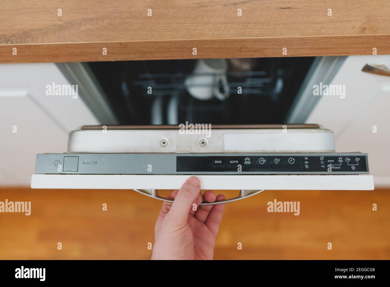 Uomo che apre o chiude la lavastoviglie in cucina. Foto Stock