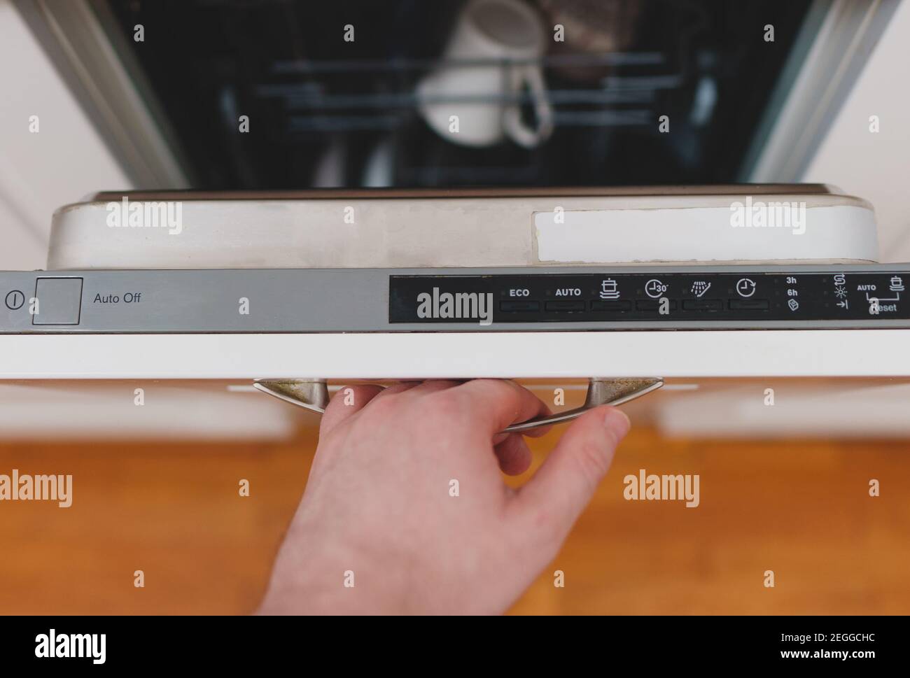 Uomo che apre o chiude la lavastoviglie in cucina. Foto Stock