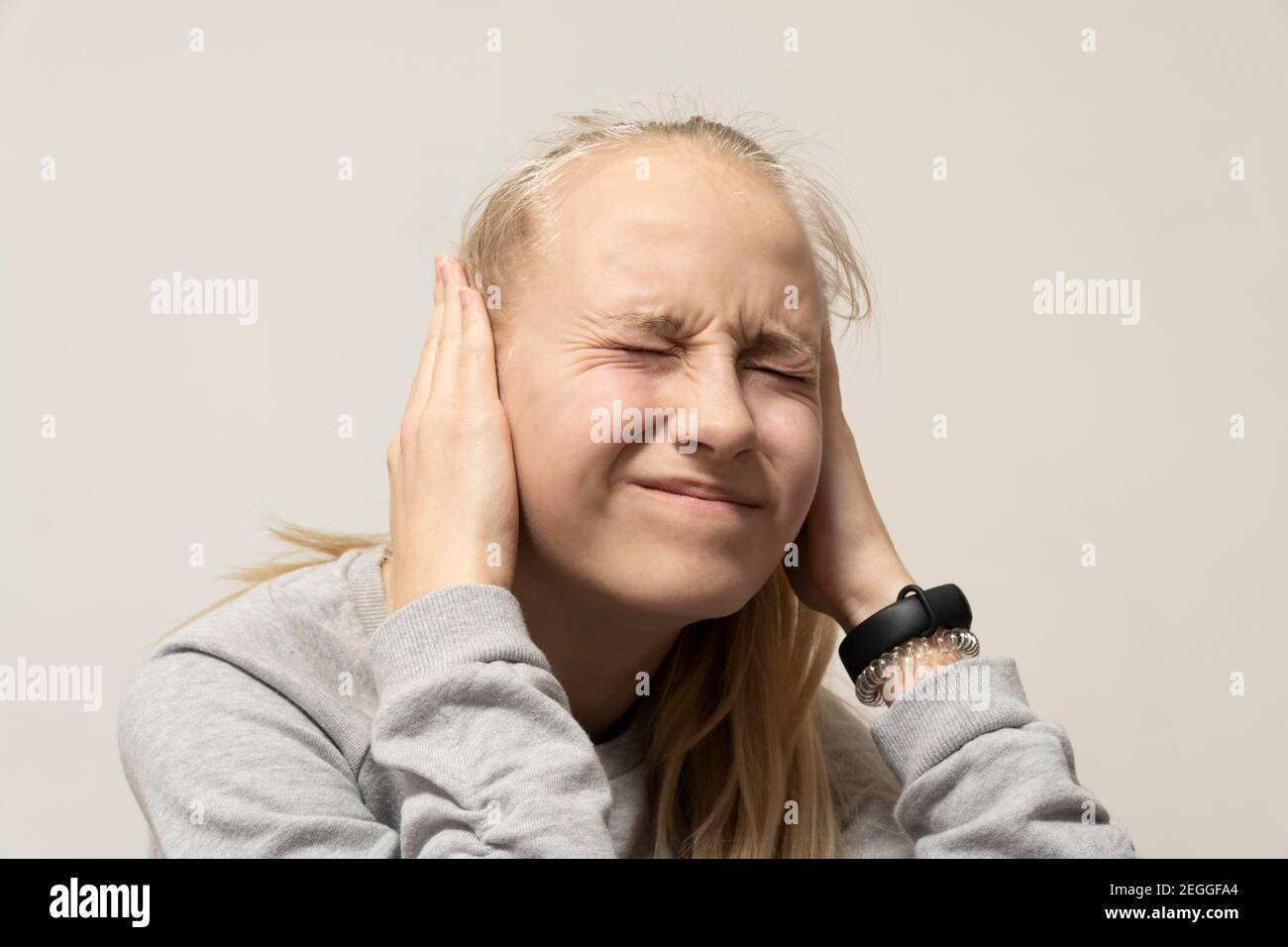 La ragazza adolescente copre le sue orecchie nel dolore. Concetto di sordità. Alta qualità Foto Stock