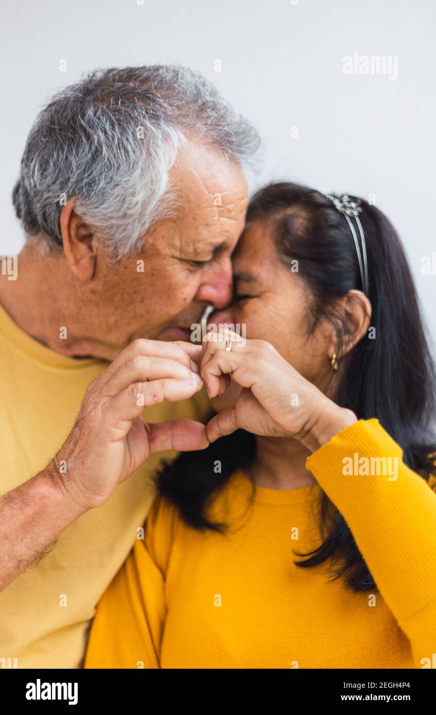 Vecchio matrimonio facendo un cuore e baciando Foto Stock