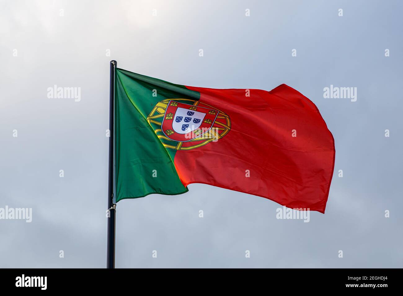 Bandiera portoghese in evoluzione, nuvole sullo sfondo Foto Stock