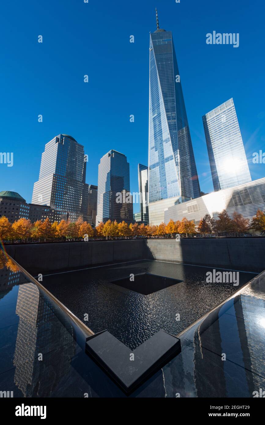 Il sole illumina le file di alberi di colore autunnale che circondano la piscina Memorial South nel National September 11 Memorial a Lower Manhattan. Foto Stock