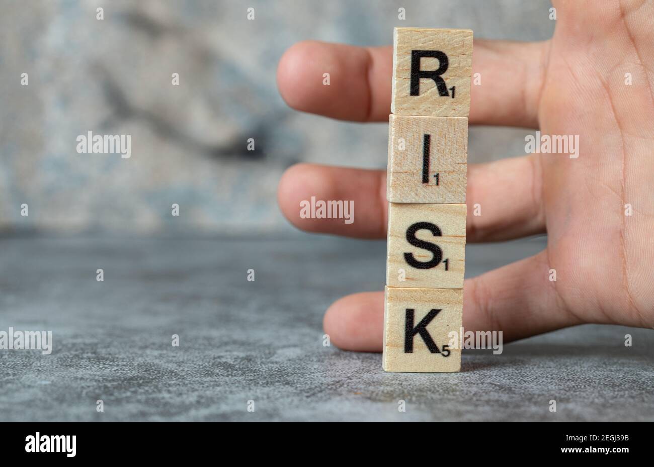 Rischio di scrittura con lettere nere su morse di legno e un uomo che lo tiene con la mano Foto Stock