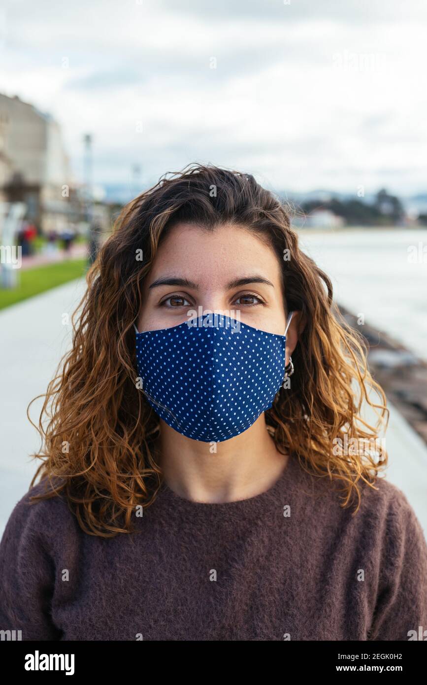 Giovane donna sulla strada che indossa una maschera facciale Foto Stock