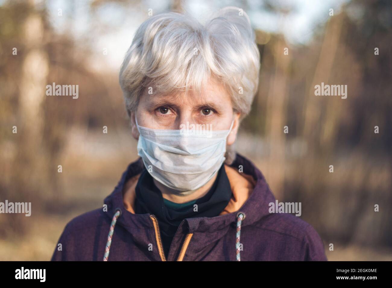 Primo piano ritratto di una donna di media età seria in piedi in strada indossando maschera medica. Il concetto di prevenzione e protezione durante una pandemia Foto Stock