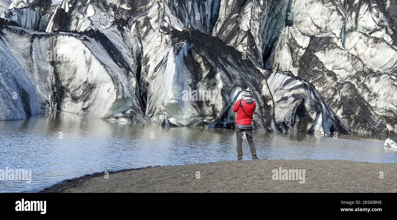 Solheimajokull, Islanda - Agosto 2019: Uomo non identificato in piedi presso il ghiacciaio di uscita Solheimajokull e la laguna glaciale in Islanda Foto Stock