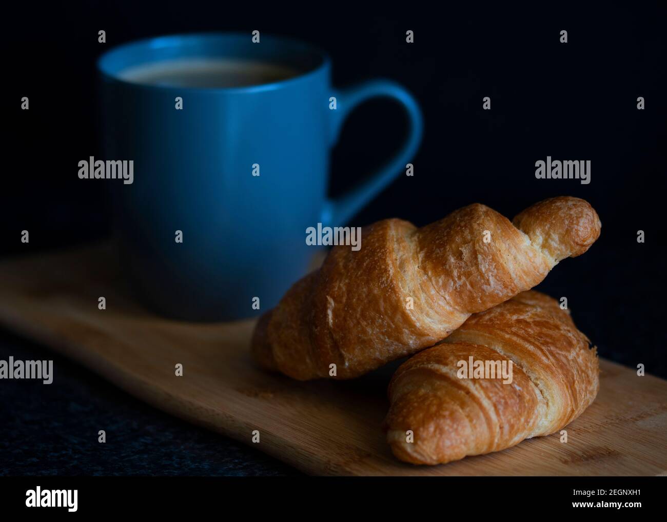 Una tazza di caffè e croissant per la colazione con un sfondo nero Foto Stock