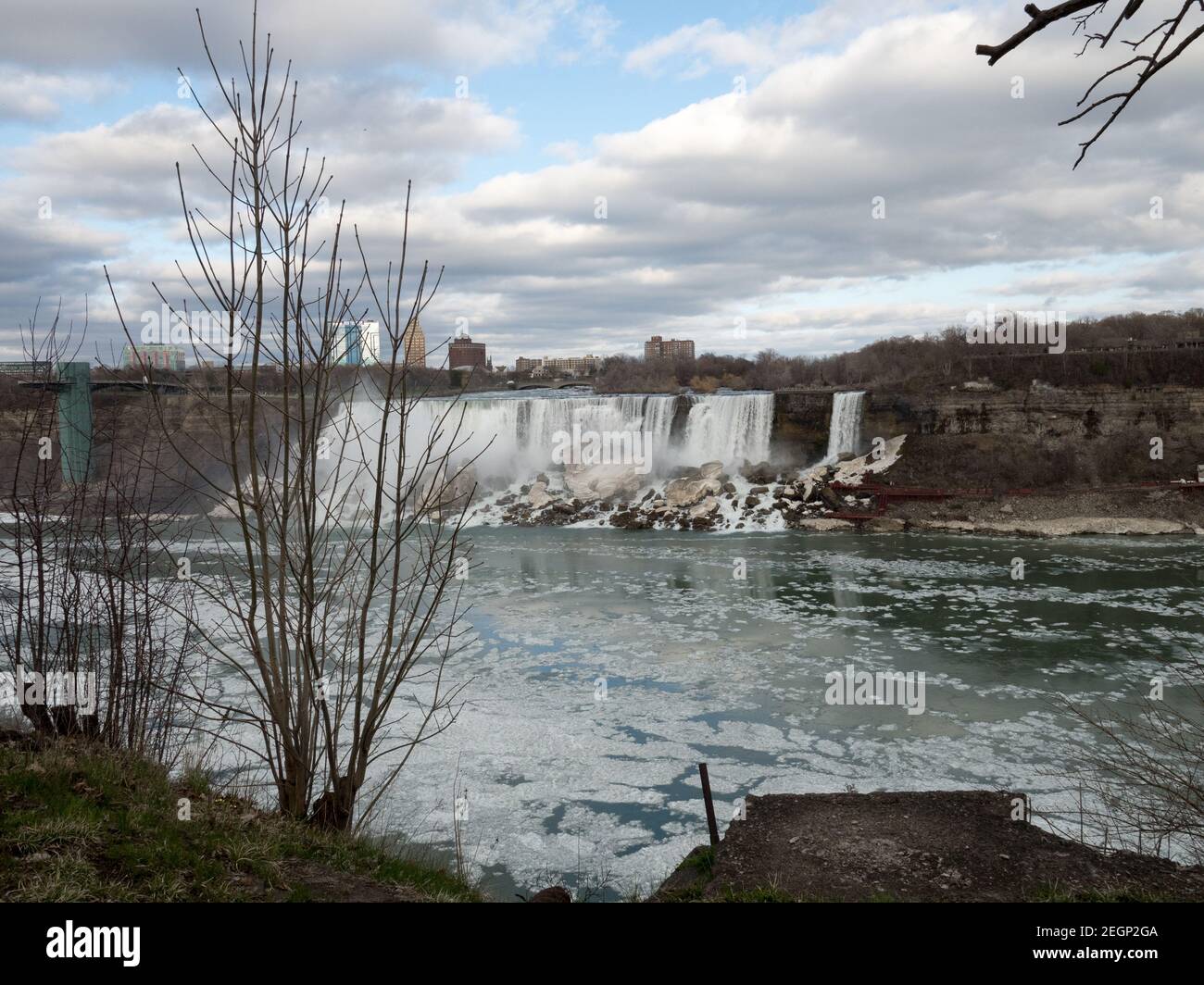 Niagara Falls lato americano visto dal Canada, ghiaccio sull'acqua e nebbia ghiacciata si trova in fondo alle cascate, cielo blu e gli edifici sul retro Foto Stock