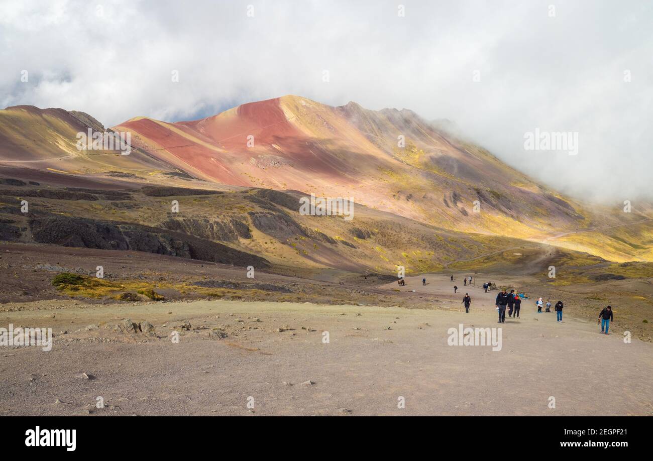 Perù, Vinicunca - 27 settembre 2019 - turisti salendo la montagna sette colori, le ombre delle nuvole creano una luce drammatica Foto Stock