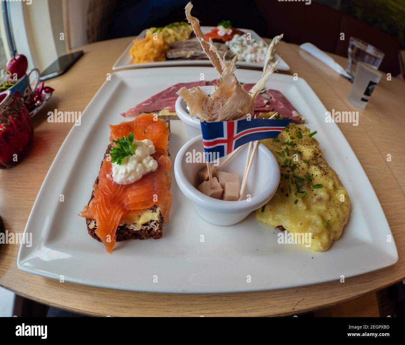 Piatto di degustazione islandese con squalo fermentato, pesce secco, trota affumicata e agnello, con bandiera islandese in cima Foto Stock