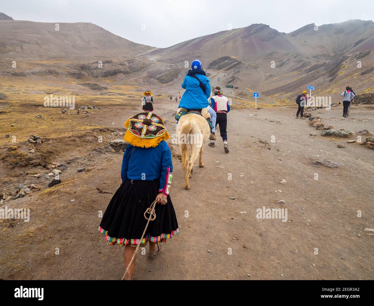 Perù, Vinicunca - 1 ottobre 2019 - turisti e locali camminano su strada sterrata verso la montagna arcobaleno, Foto Stock