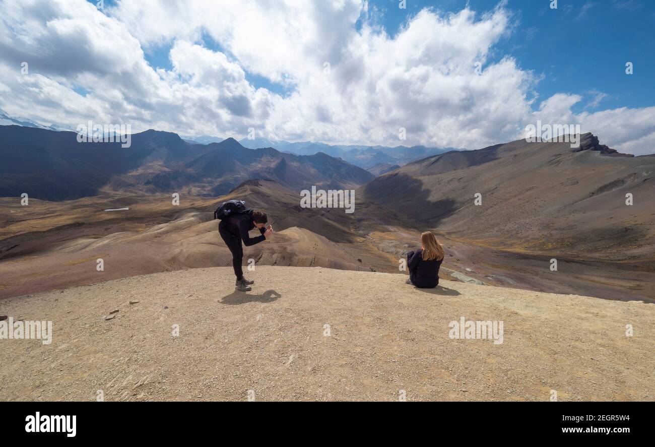 Perù, Vinicunca - 1 ottobre 2019 - l'uomo scatta foto di donna di fronte al paesaggio montano stupefacente Foto Stock