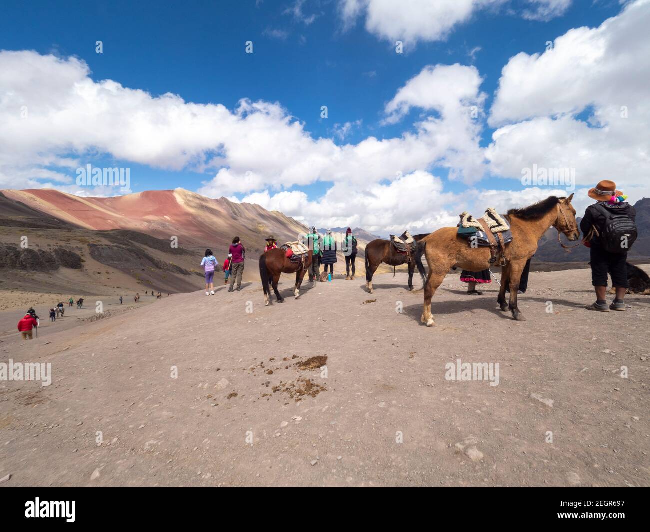 Perù, Vinicunca - 1 ottobre 2019 - turisti e cavalli in cima a una montagna sotto il cielo blu Foto Stock