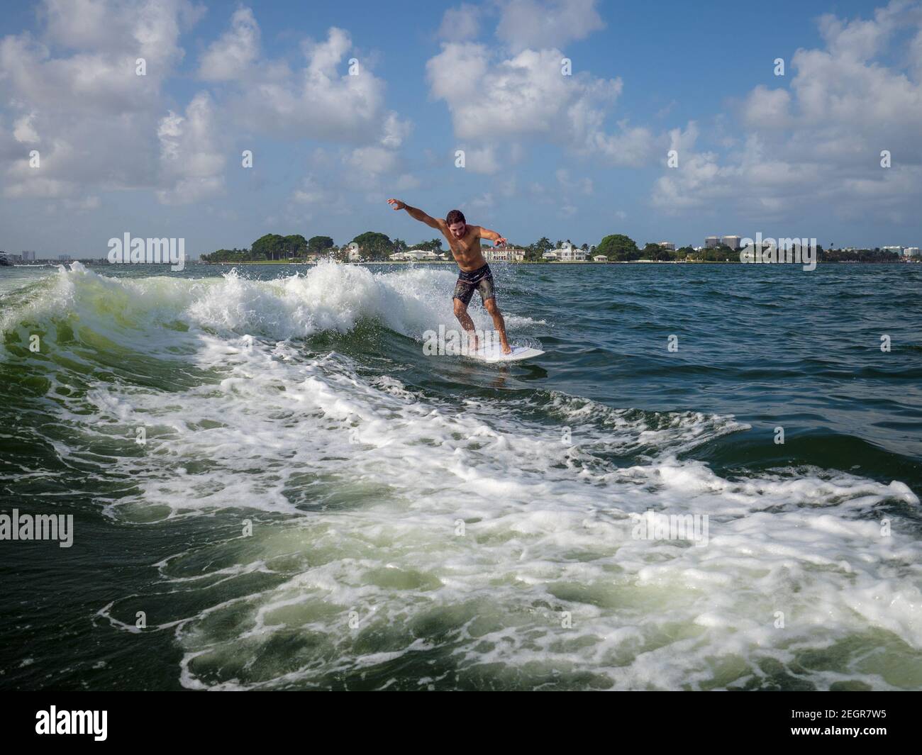 Il maschio si muove molto velocemente come egli svegli surfs onda in mare, ha le braccia in su per mantenere l'equilibrio Foto Stock