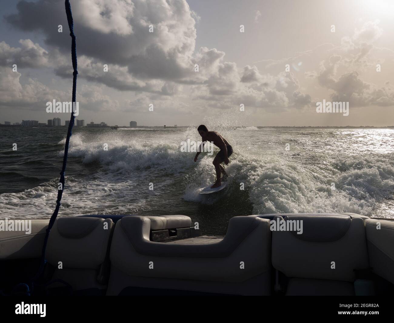 Ripresa illuminata all'indietro di uomo wake surfing dietro la barca a. Miami Beach Foto Stock