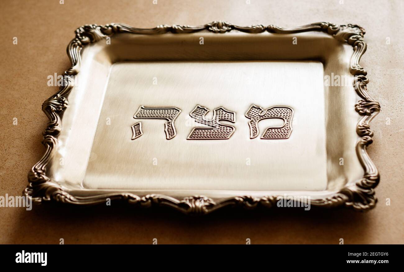 Un vassoio d'argento con la parola matzah scritta in ebraico, progettato per matzah, che è un pane speciale per la Pasqua Foto Stock