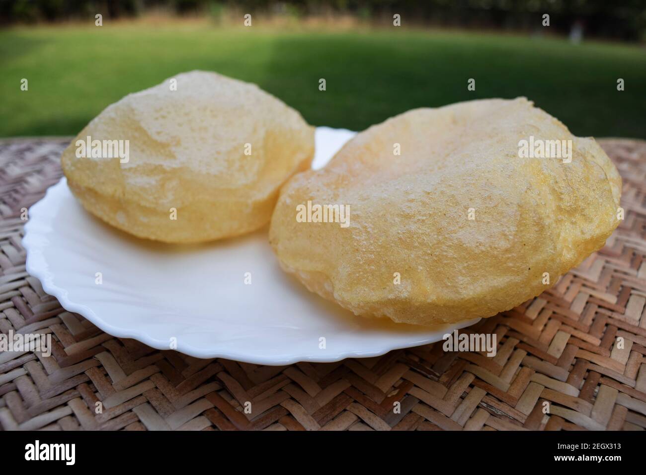 puri semplice o pane fritto indiano servito su piatto bianco. Farina integrale soffiata, portata principale o colazione tradizionale. Sfondo Foto Stock