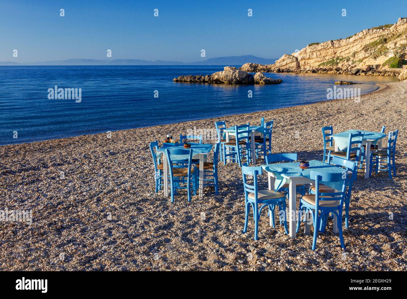 Sedie e tavolo di un ristorante greco sulla spiaggia di Kokkari, nell'isola di Samos, Grecia, Europa. Foto Stock