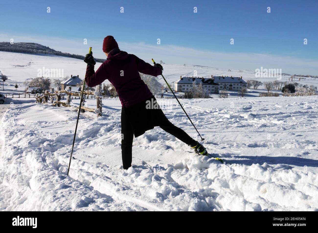 Paesaggio innevato con donna sciatrice in neve Repubblica Ceca donna che cammina in campagna inverno pali da passeggio vista posteriore Foto Stock