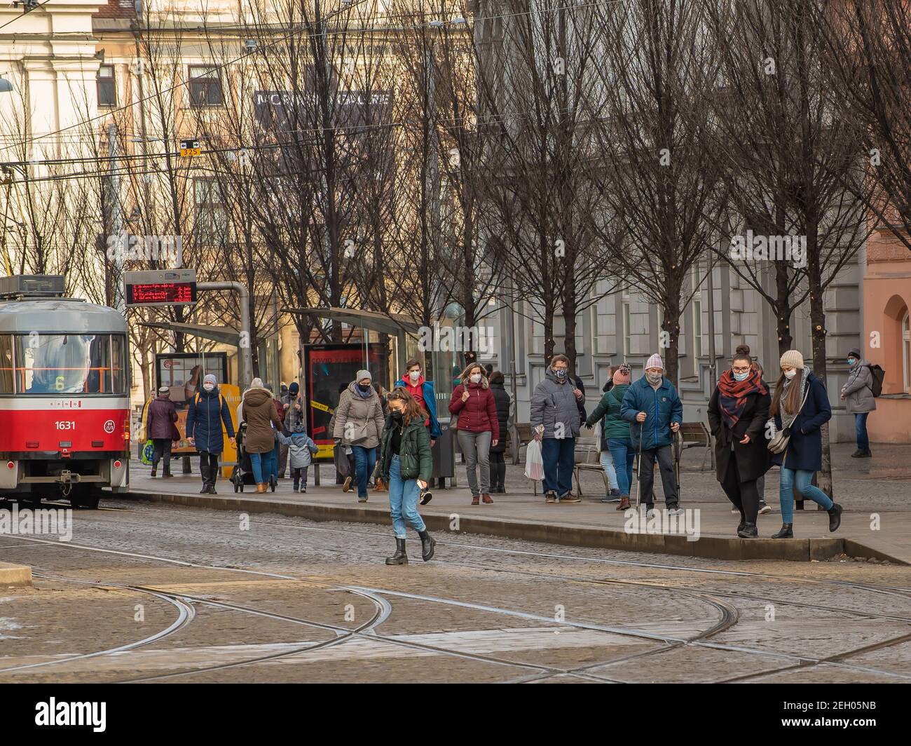 Brno, Repubblica Ceca. 02-17-2021. Persone con maschera per proteggere dal virus corona a piedi sulla fermata del tram Cheska nella città di Brno in fredda giornata invernale. Foto Stock