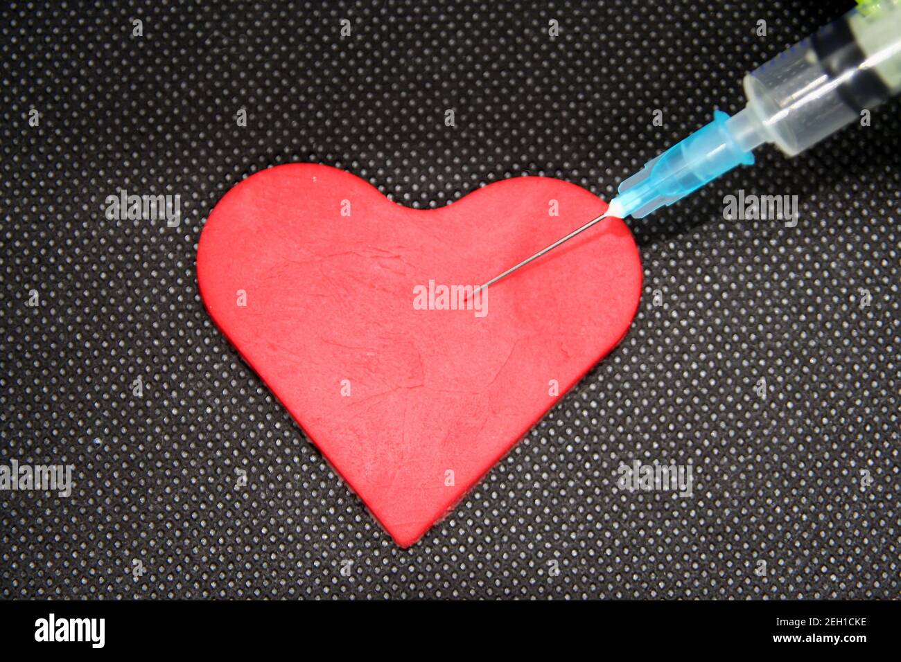 Siringa medica e un cuore. Oggetto a forma di cuore e una cura. Foto Stock