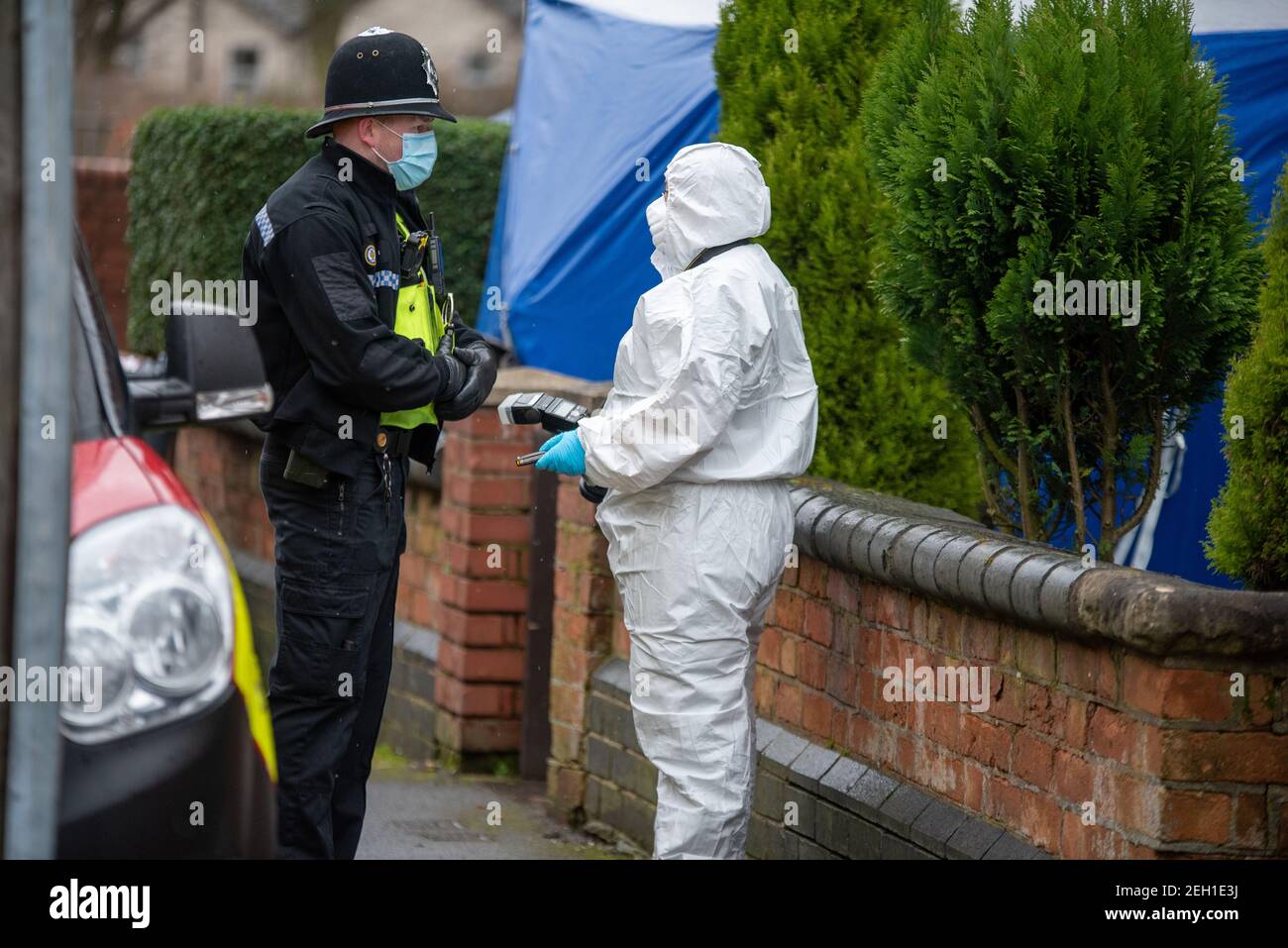 Handsworth, Birmingham, West Midlands, Regno Unito. 19 febbraio 2021: L'ufficiale forense parla con un ufficiale di polizia sulla scena. Un uomo è morto dopo una beatola in una proprietà su Church Hill Road intorno alle 5:20 venerdì mattina. Gli ufficiali di Forensics hanno combattuto la casa e una tenda blu rimane fuori della proprietà. Credit: Ryan Underwood / Alamy Live News. Foto Stock