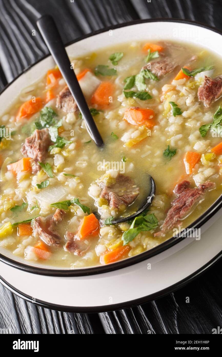 Il brodo Scotch è una tradizionale zuppa scozzese a base di agnello e verdure, orzo, piselli nel piatto sul tavolo. Verticale Foto Stock