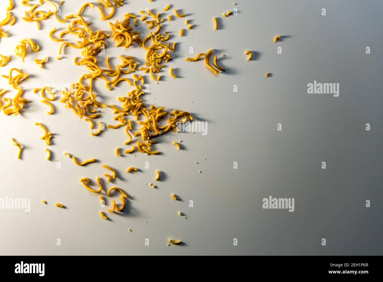 Piccolo pezzo spaghetti istantanei scattered circa sul pavimento Foto Stock