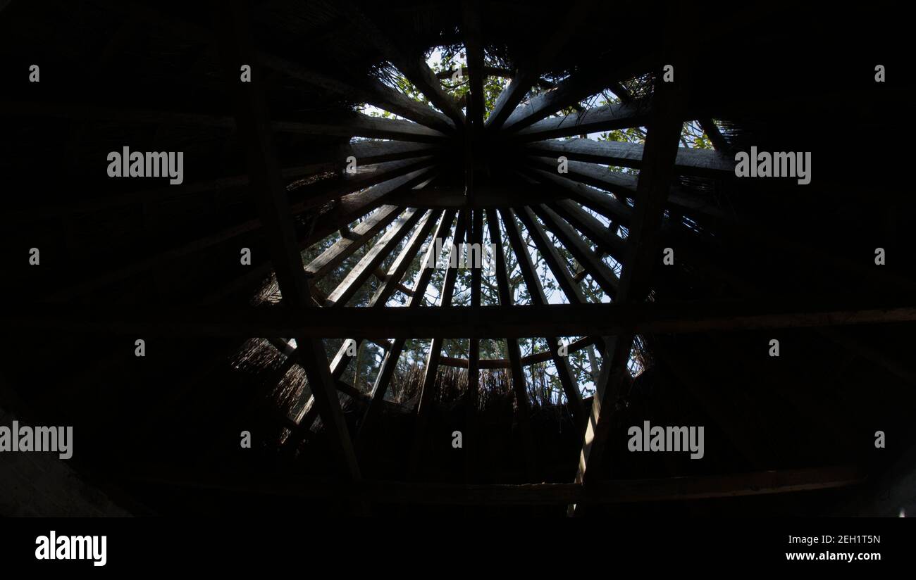 Guardando verso l'alto attraverso il tetto di legno di un vecchio edificio circolare che ha perso la sua paglia. Foto Stock