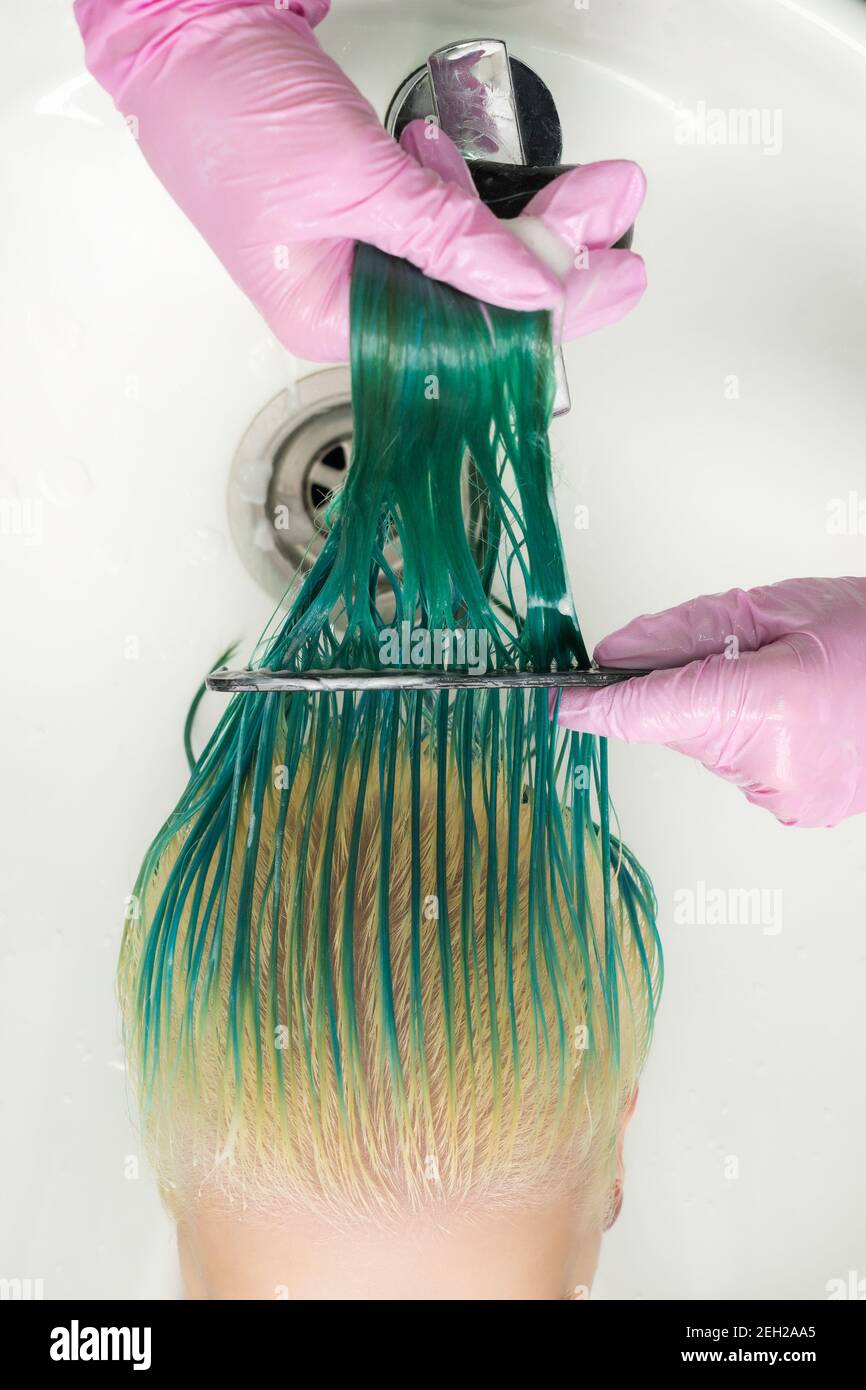 Foto ad alto angolo del parrucchiere in un guanto protettivo che tiene i  capelli bagnati nelle