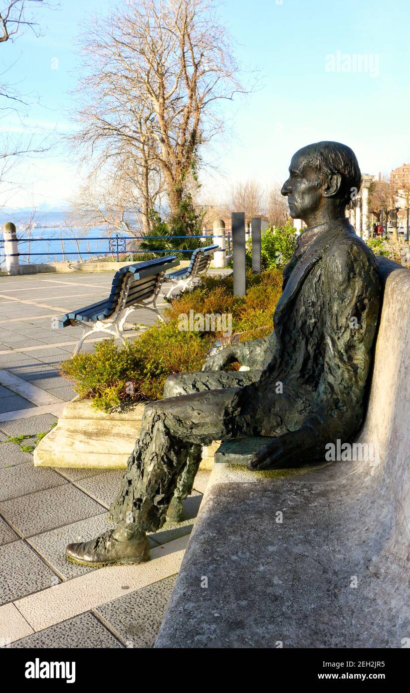 Statua in bronzo seduta del poeta Gerardo Diego Cendoya su una panca di cemento che guarda al mare Santander Cantabria Spagna Inverno sole Foto Stock