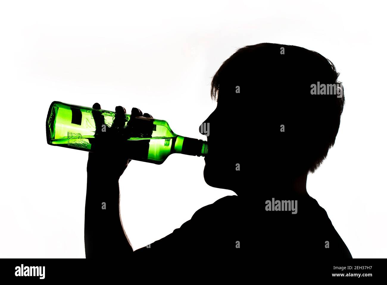 Silhouette di un anonimo adolescente che beve alcol da una bottiglia Foto Stock