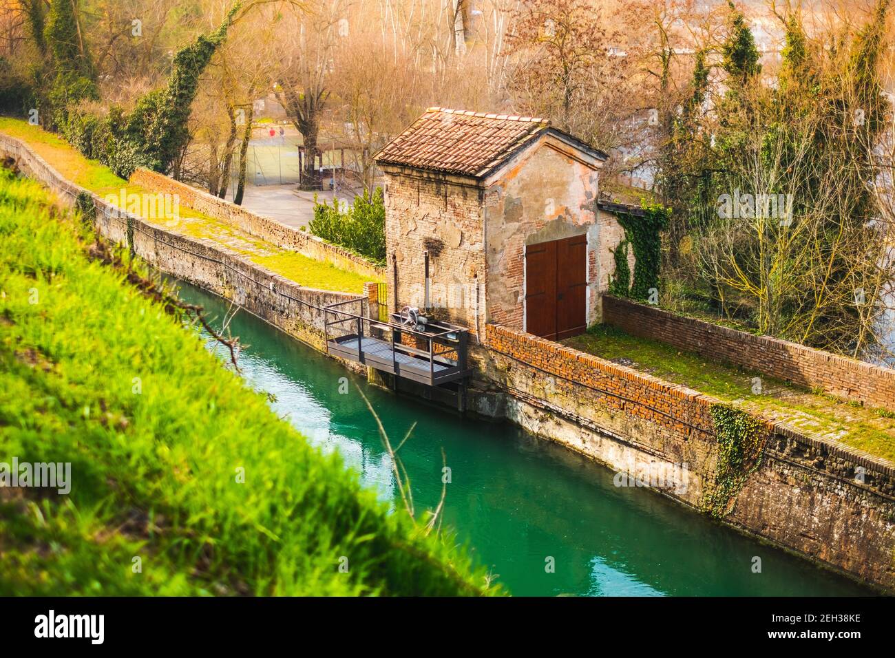antica struttura della serratura del fiume lungo il canale circondato da vegetazione spessa Foto Stock