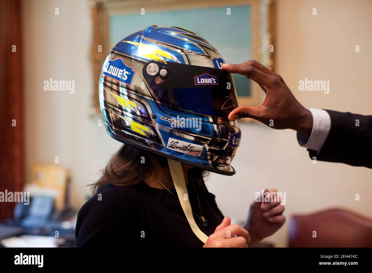 Il segretario personale del presidente Barack Obama, Katie Johnson, prova sul casco NASCAR di Jimmie Johnson come assistente personale Reggie Love solleva la visiera, 19 agosto 2009. Foto Stock