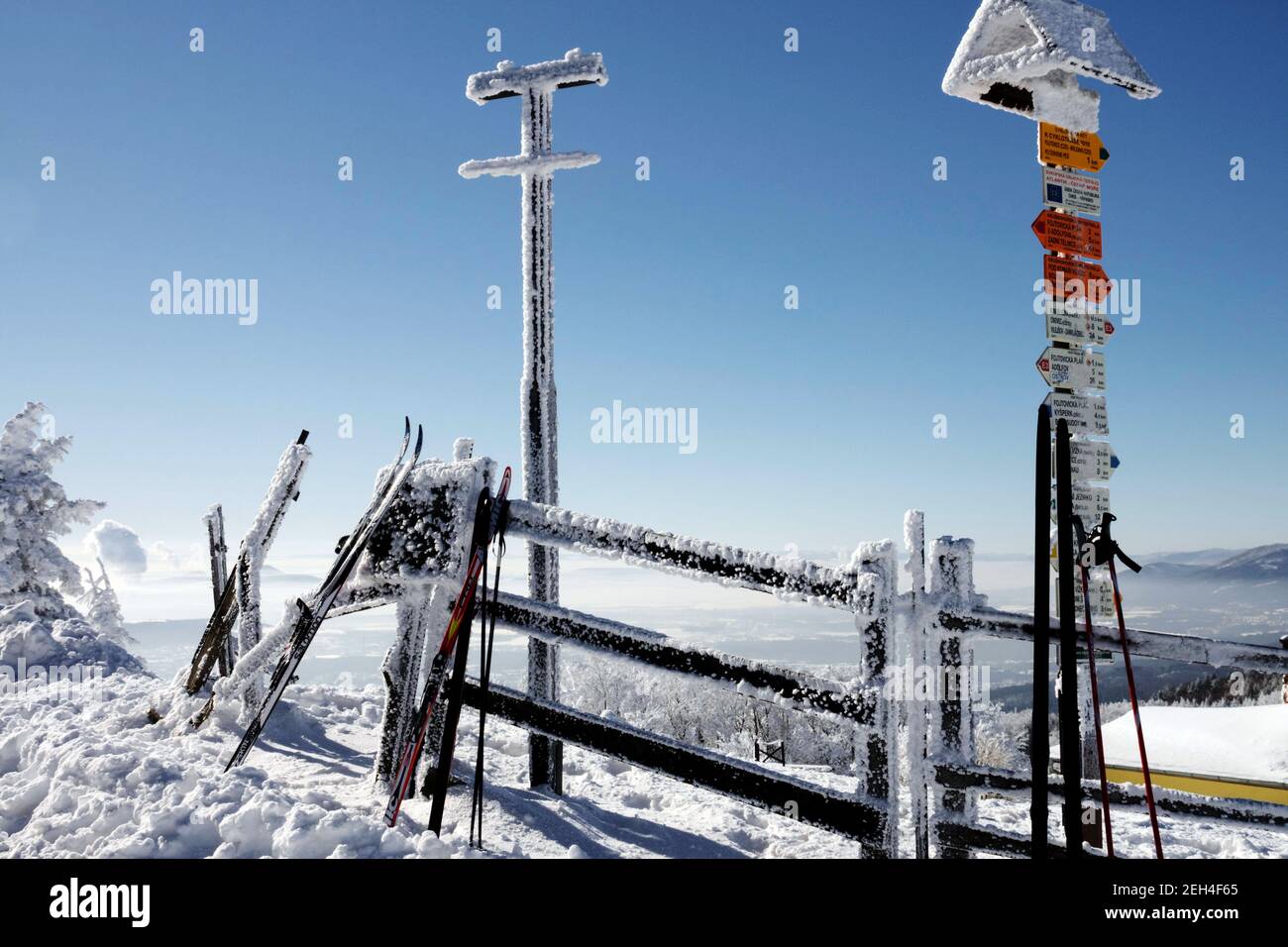 Portasci presso il cartello turistico, giorno invernale di sole neve, segnaletica per escursioni a piedi cielo blu di montagna Foto Stock