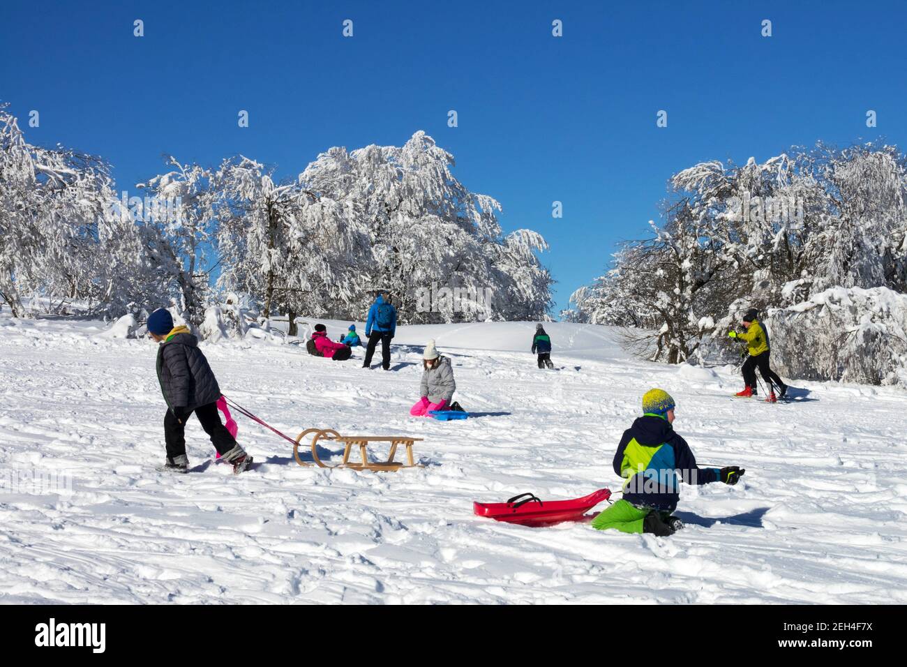 Bambini che dormono in inverno sulla neve godendo di una giornata di sole Foto Stock