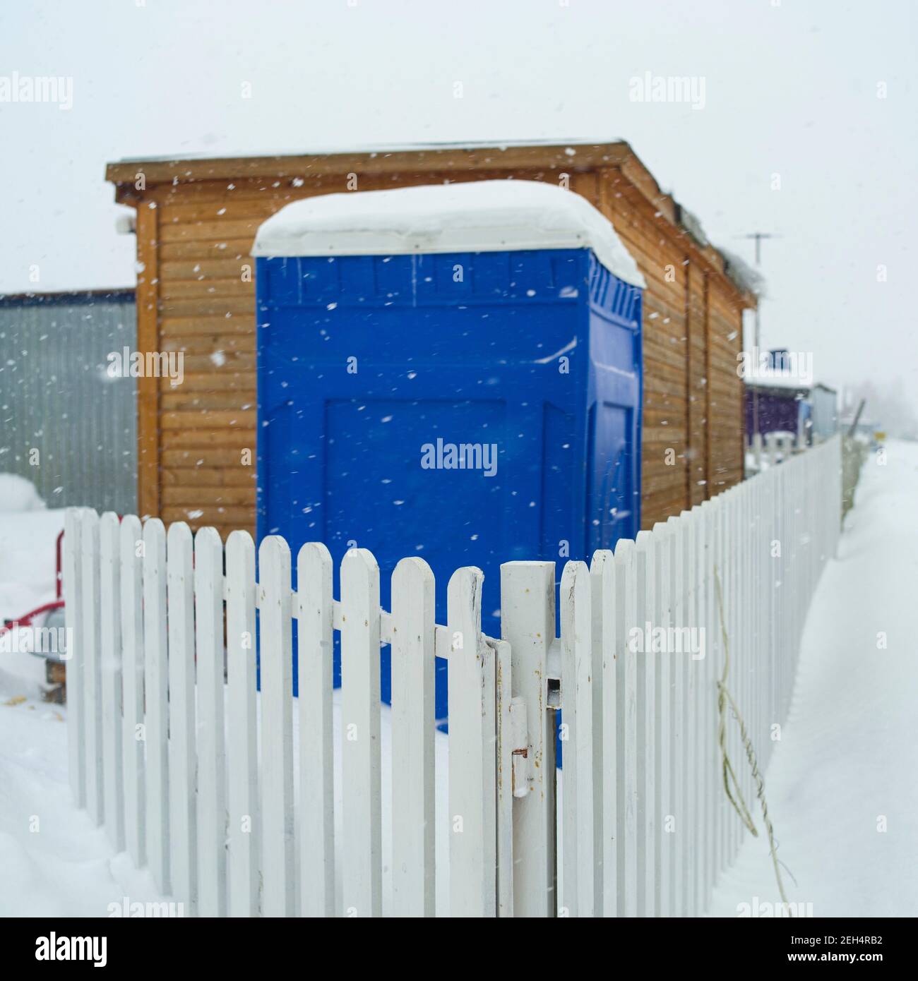 wc pubblico trasportabile in PVC dietro la recinzione, messa a fuoco in primo piano, scena invernale Foto Stock