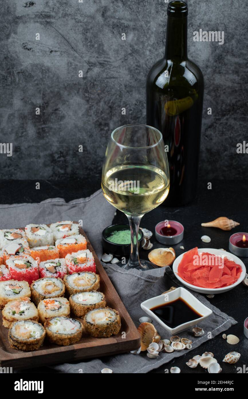 Sushi misto su tavola di legno con una bottiglia e un bicchiere di vino  bianco Foto stock - Alamy