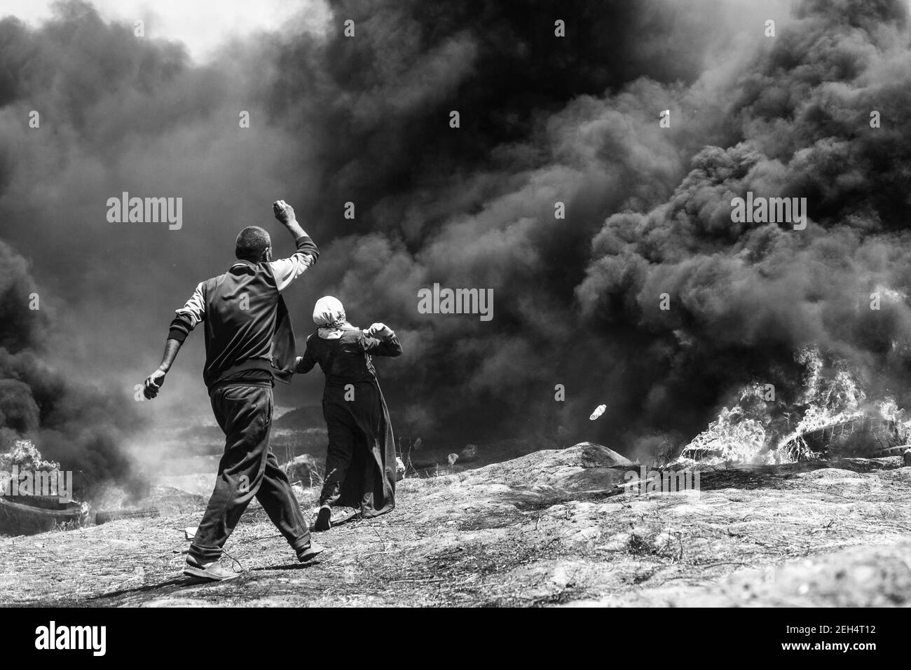 Una donna getta pietre mentre gli uomini palestinesi usano le armi per gettare pietre in risposta all'intervento delle forze israeliane durante una manifestazione organizzata il 70° anniversario del Nakba, noto anche come giorno della catastrofe nel 1948, e contro i piani della Gerusalemme degli Stati Uniti. 14 maggio 2018. Malaka. Striscia di Gaza. Palestina. Foto Stock